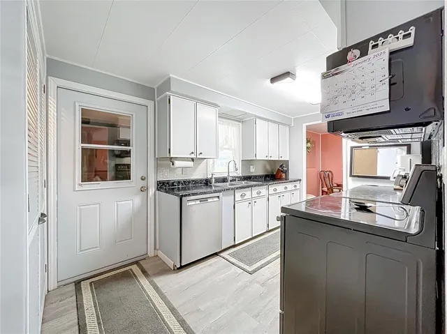 a kitchen with granite countertop white cabinets and a stove top oven