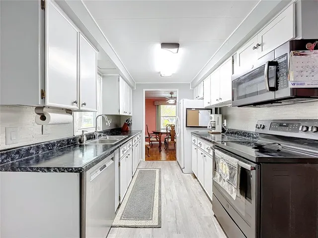 a kitchen with granite countertop a sink stainless steel appliances and cabinets