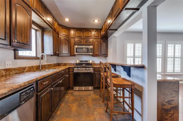 a kitchen with stainless steel appliances granite countertop sink stove top oven and cabinets