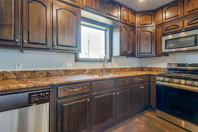 a kitchen with stainless steel appliances granite countertop a sink and a stove