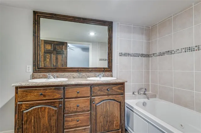 a bathroom with a granite countertop sink mirror and a bathtub