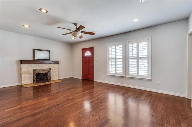 a view of an empty room with wooden floor fireplace and a window