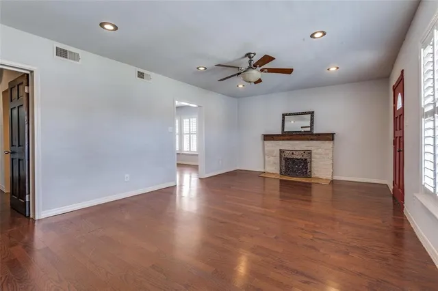 a view of an empty room with window and wooden floor