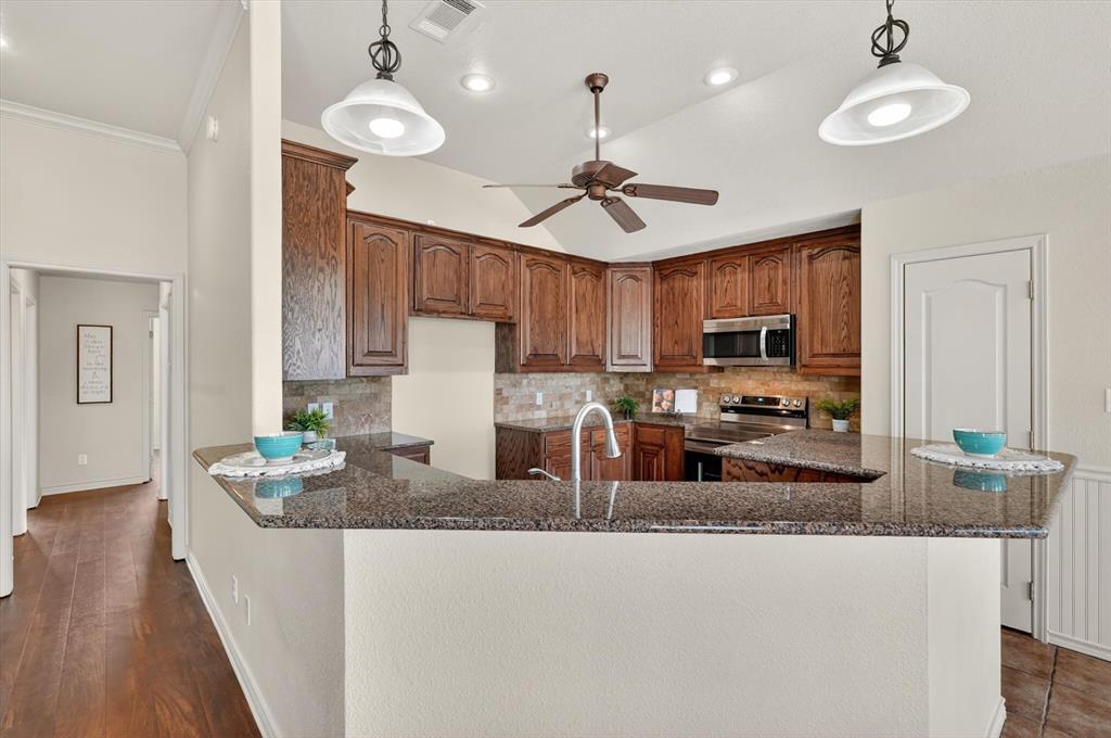 2828 Bennett Road Howe, TX 75459 - Photo 13 of 39 a kitchen with granite countertop a stove a sink a counter space and cabinets