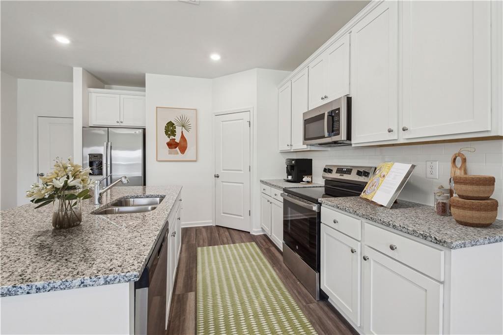 3373 Fence Road Northeast, Unit TH2 Dacula, GA 30019 - Photo 23 of 36 a kitchen with stainless steel appliances granite countertop a sink dishwasher and cabinets with wooden floor