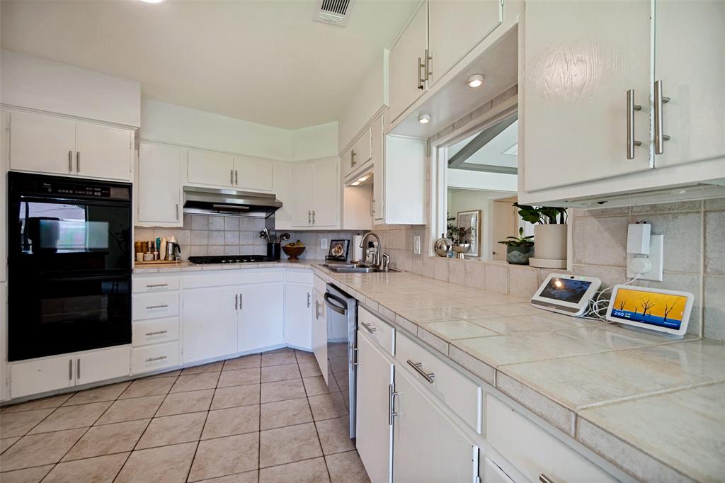 4614 Ridgeside Drive Dallas, TX 75244 - Photo 12 of 30 Kitchen featuring white cabinetry, tile countertops, integrated double oven, stainless steel dishwasher, and a tile backsplash