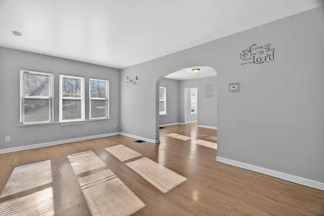 a view of an empty room with window and wooden floor
