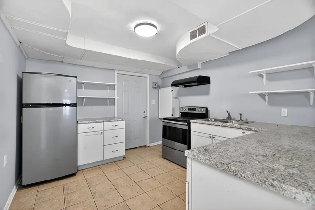 a kitchen with white cabinets and refrigerator