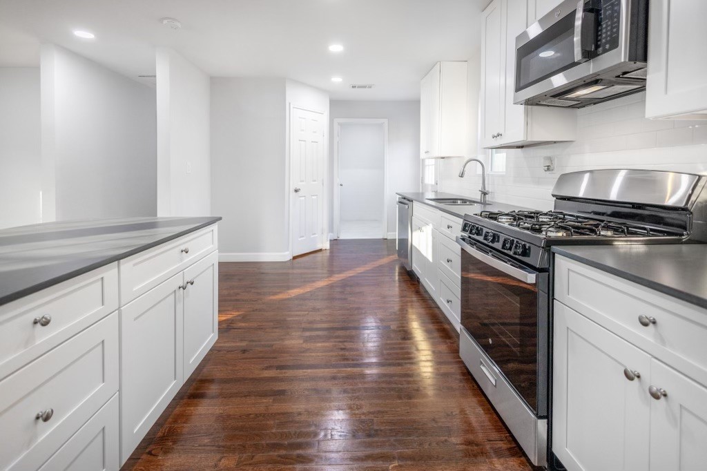3234 Berry Street Houston, TX 77004 - Photo 17 of 34 a kitchen with granite countertop wooden floors and stainless steel appliances