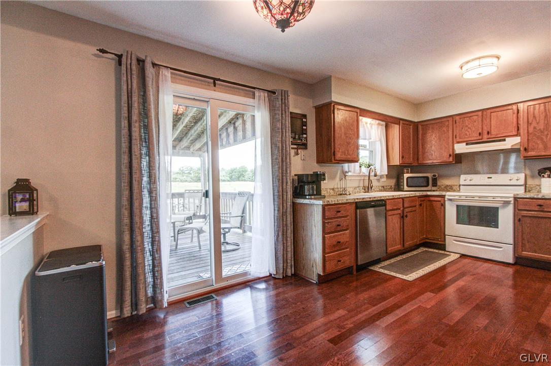 2023 Clover Mill Road Quakertown, PA 18951 - Photo 15 of 48 a kitchen with stainless steel appliances granite countertop a refrigerator a sink dishwasher a stove and a dining table with wooden floor