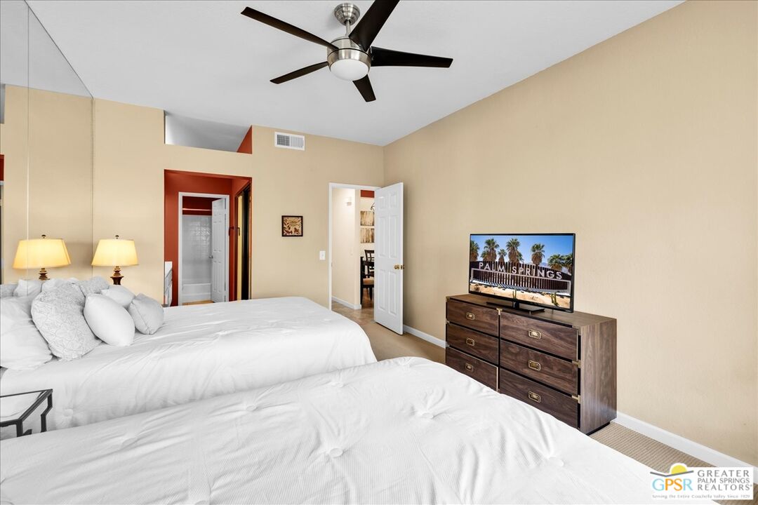 401 El Cielo Road, Unit 147 Palm Springs, CA 92262 - Photo 20 of 44 a bedroom with a bed and dresser with mirror