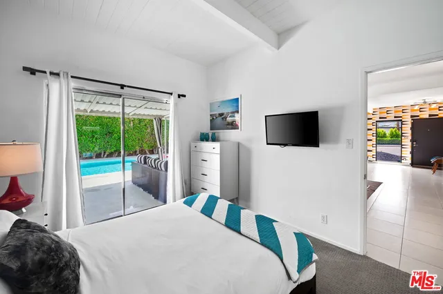 a bedroom with a bed tv and a large window