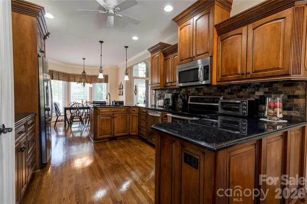 a kitchen with granite countertop a stove a sink a refrigerator and wooden floor