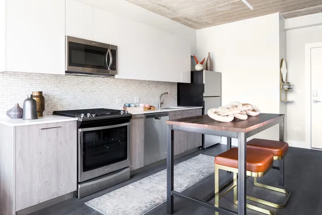 a kitchen with stainless steel appliances a stove a sink cabinets and a dining table