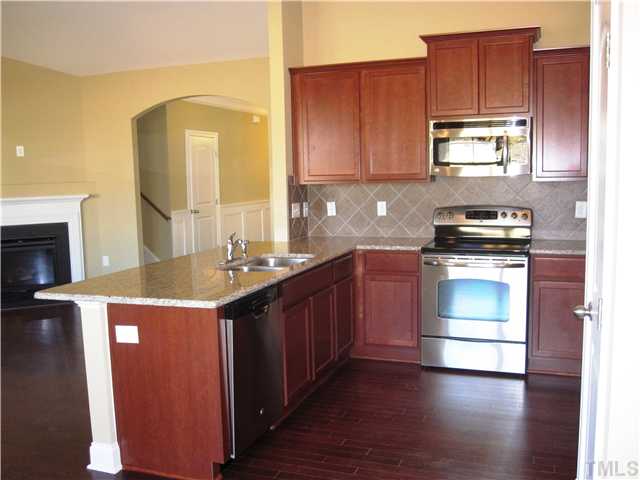 7639 Birchmoor Way, Unit LT91 Raleigh, NC 27616 - Photo 8 of 15 a kitchen with kitchen island granite countertop wooden cabinets and a stove