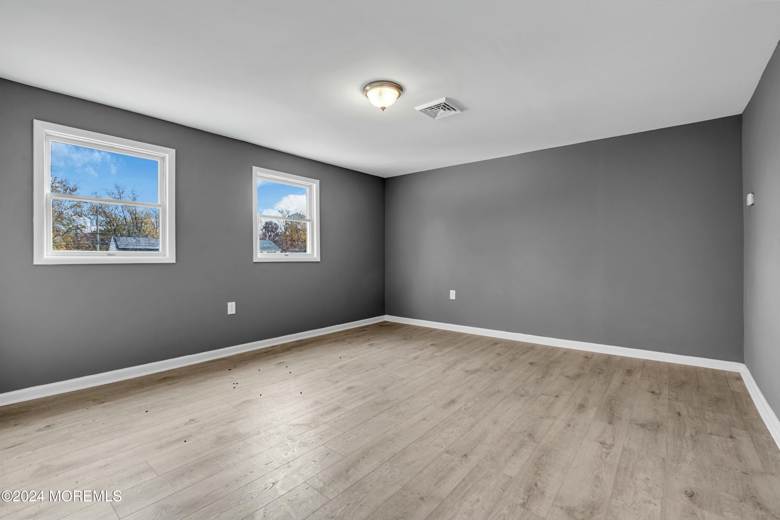 211 Delaware Avenue, Unit 2 Cliffwood, NJ 07721 - Photo 5 of 16 a view of an empty room with wooden floor and a window