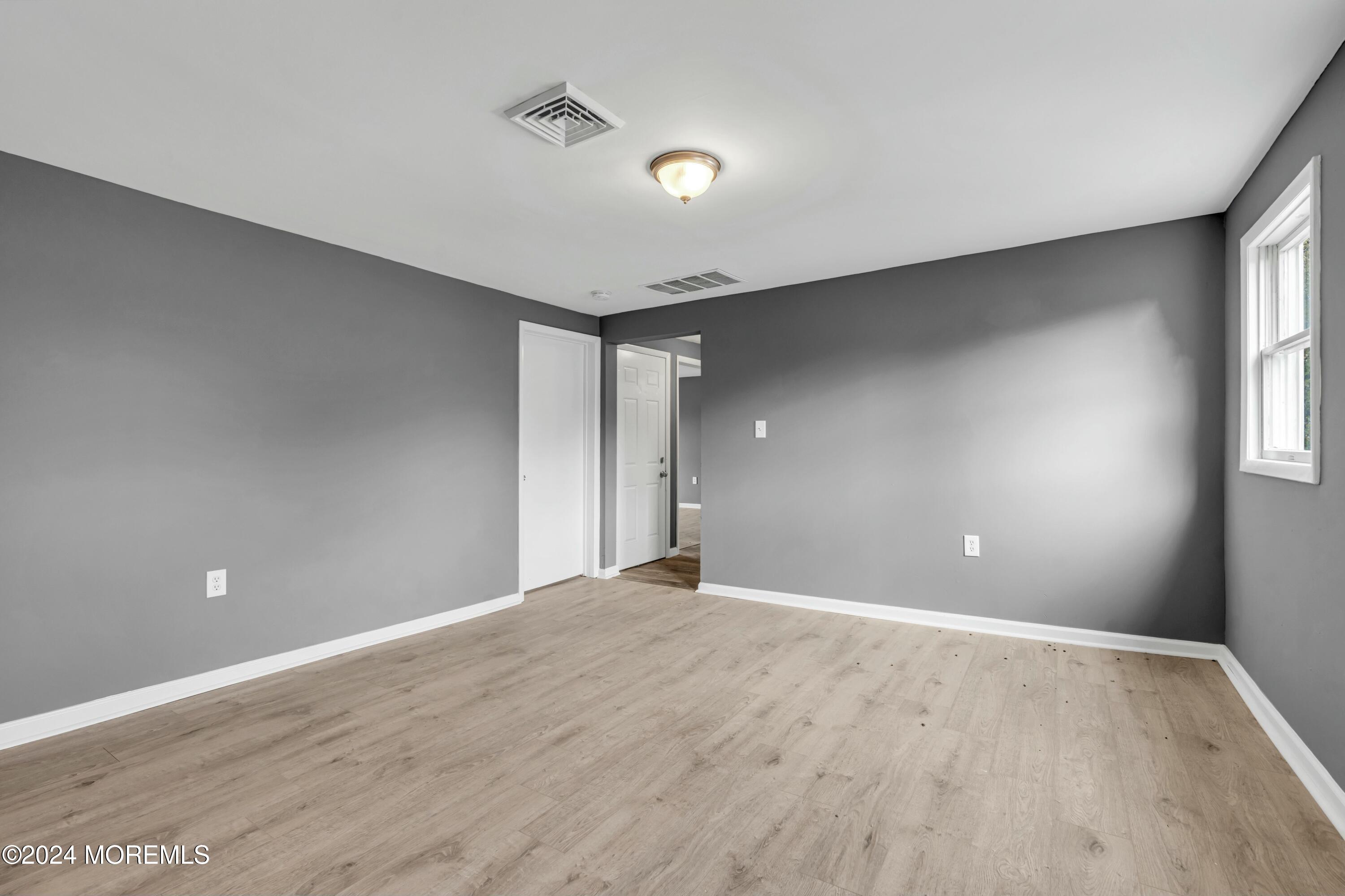 211 Delaware Avenue, Unit 2 Cliffwood, NJ 07721 - Photo 7 of 16 a view of an empty room with wooden floor and a window