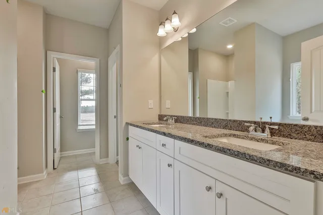 a bathroom with a granite countertop sink a mirror and a shower