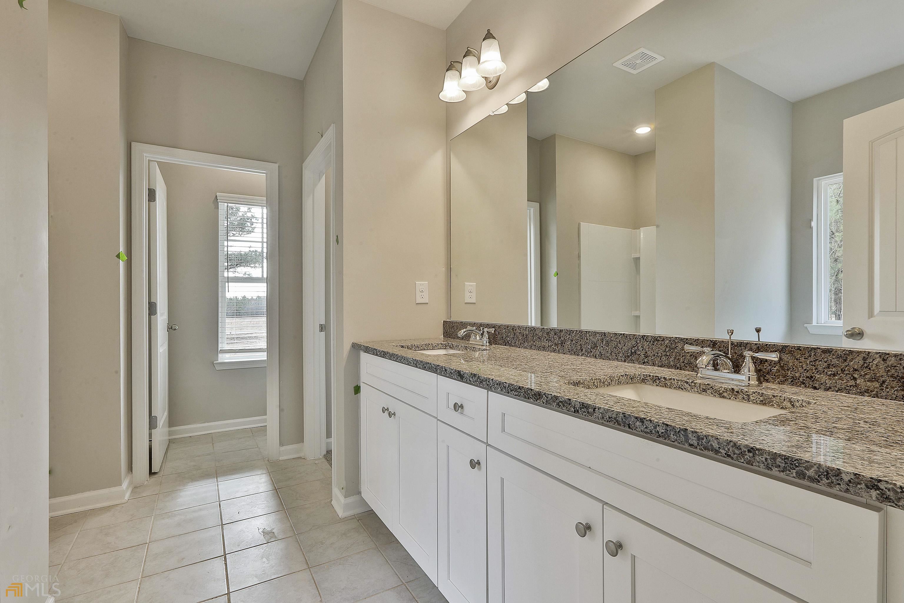 3575 Strickland Town Road Luthersville, GA 30251 - Photo 19 of 29 a bathroom with a granite countertop sink a mirror and a shower