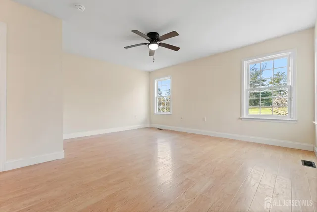 a view of an empty room with a window and wooden floor