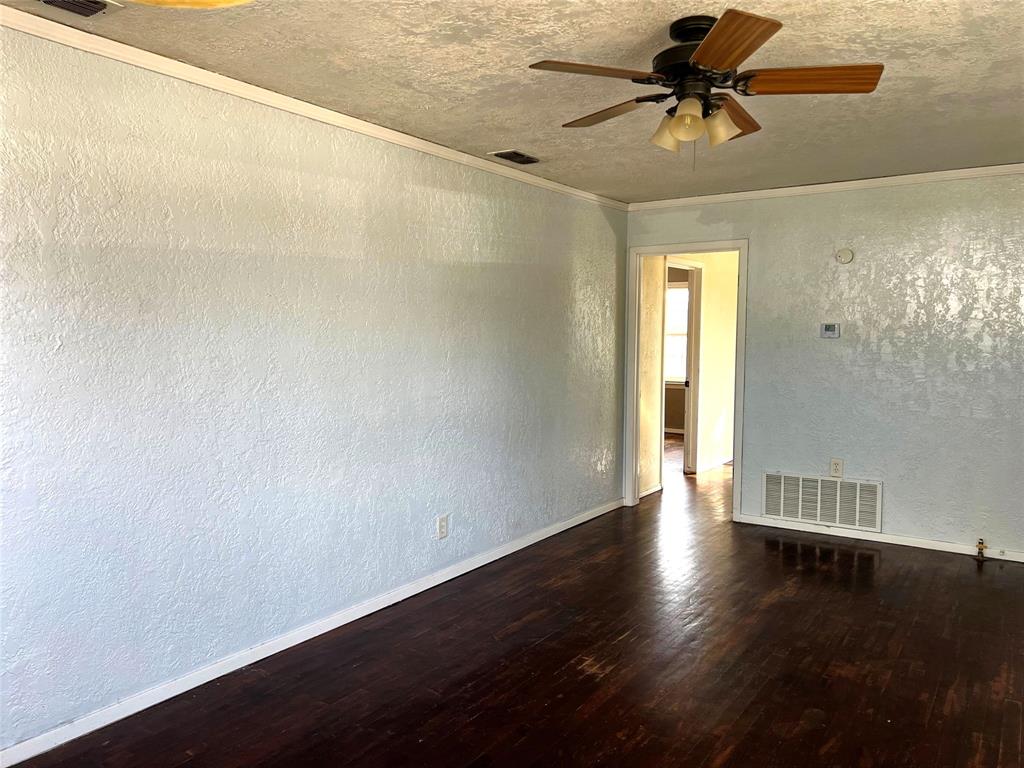 402 South Red River Street Henrietta, TX 76365 - Photo 11 of 20 an empty room with wooden floor chandelier fan and windows