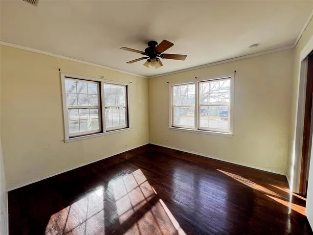a view of an empty room with window and wooden floor