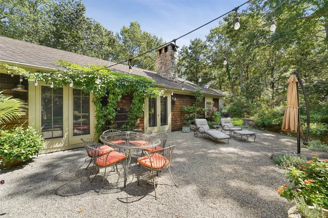a view of a patio with table and chairs potted plants and large tree