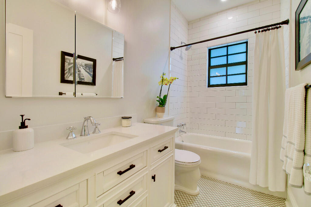 623 Avon Road West Palm Beach, FL 33401 - Photo 19 of 39 a bathroom with a granite countertop sink a toilet a mirror a vanity a bathtub and shower