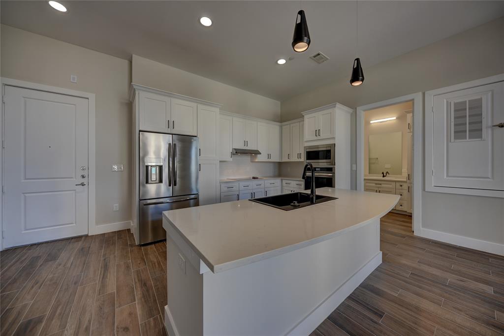 a large kitchen with stainless steel appliances kitchen island a large counter top and wooden floors