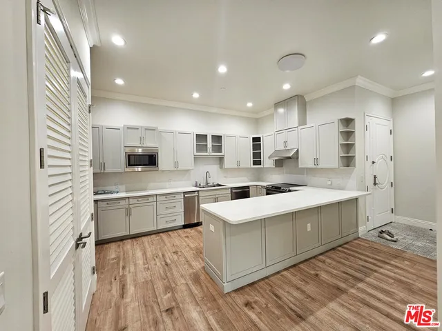 a large kitchen with a large counter top a sink stainless steel appliances and cabinets