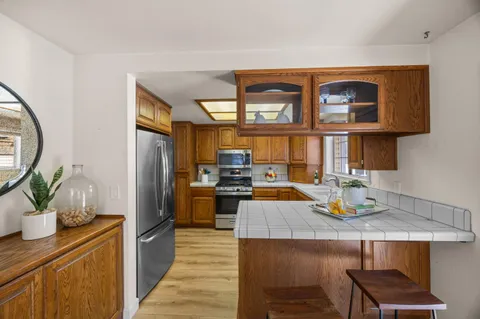 a living room with stainless steel appliances kitchen island granite countertop a table chairs in it and a wooden floor