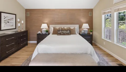 a large bed sitting in a bedroom next to a window with lamp