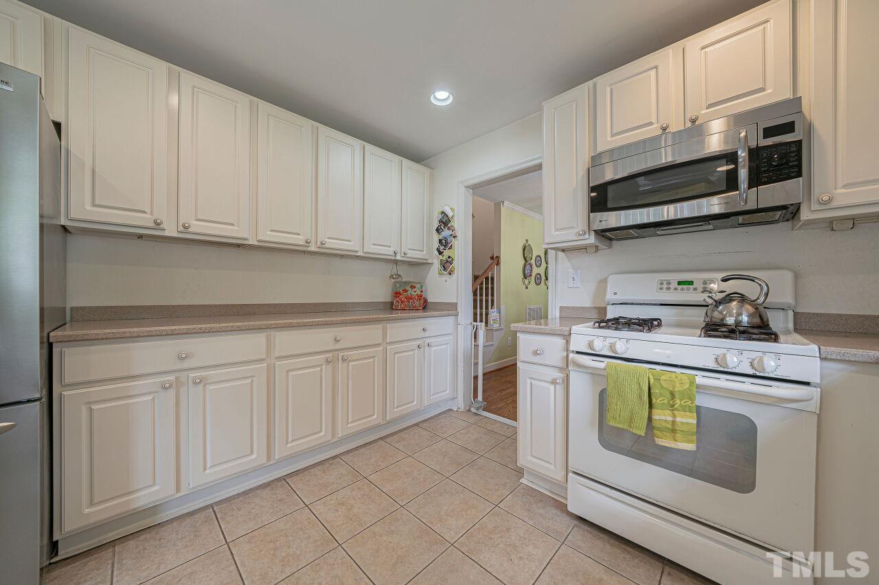 2617 Grant Avenue Raleigh, NC 27608 - Photo 19 of 28 a kitchen with stainless steel appliances granite countertop a sink and a stove top oven with white cabinets