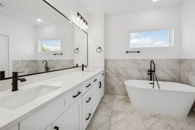 a bathroom with a double vanity sink mirror and bathtub