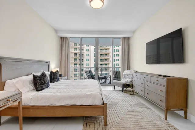 a bedroom with a large bed and a flat tv screen on dresser