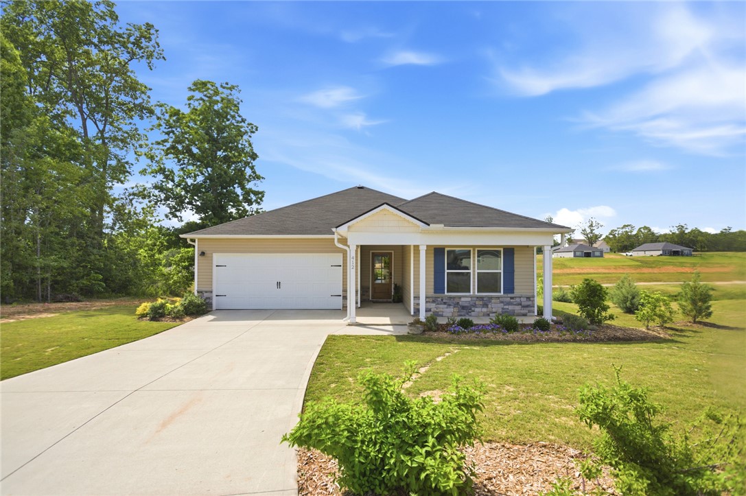 This appealing single-story residence boasts a practical garage and a welcoming front porch, all set on a well-maintained lawn.