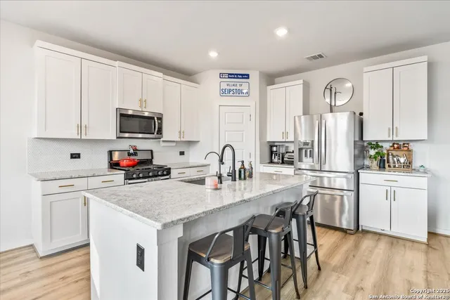 a kitchen with granite countertop white cabinets and stainless steel appliances