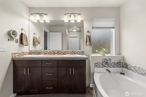 a bathroom with a double vanity sink mirror and bathtub