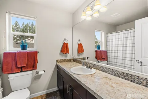 a bathroom with a granite countertop sink a mirror and a toilet