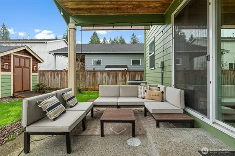 a view of a patio with couches table and chairs with wooden floor and fence