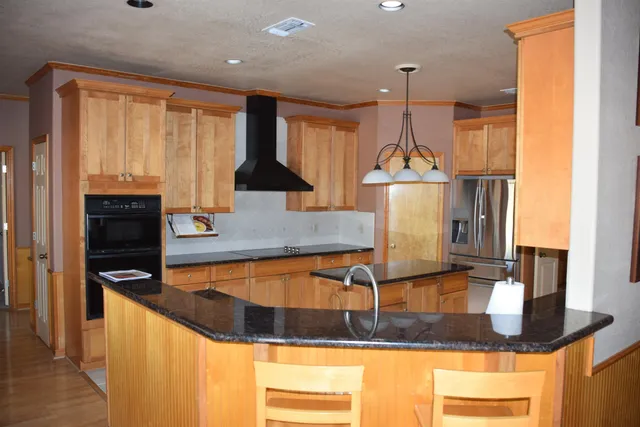 a kitchen with kitchen island granite countertop a sink a counter top space and cabinets