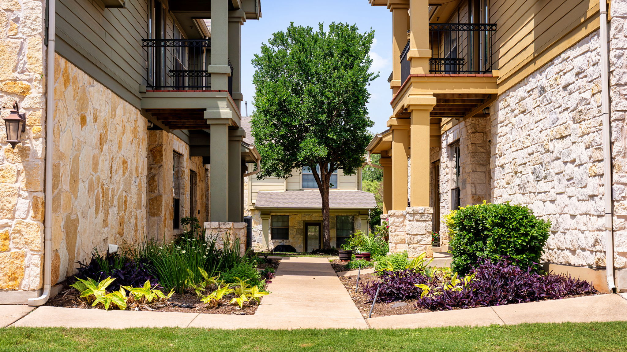 14815 Avery Ranch Boulevard, Unit 1401 Austin, TX 78717 - Photo 25 of 38 Stonework exterior with balconies and a central tree-lined walkway