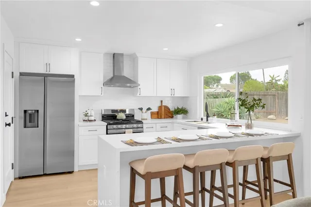 a kitchen with stainless steel appliances granite countertop a stove a refrigerator a sink dishwasher a dining table and chairs with wooden floor