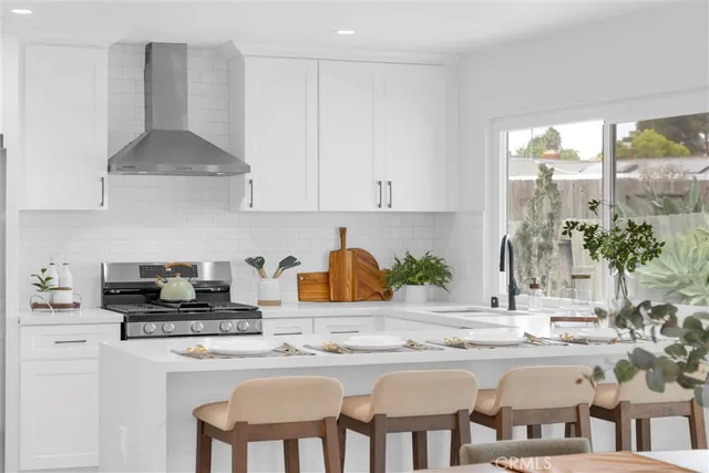 a kitchen with stainless steel appliances a sink a stove a table and chairs in it