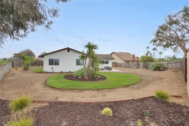 a view of a house with a backyard and bushes