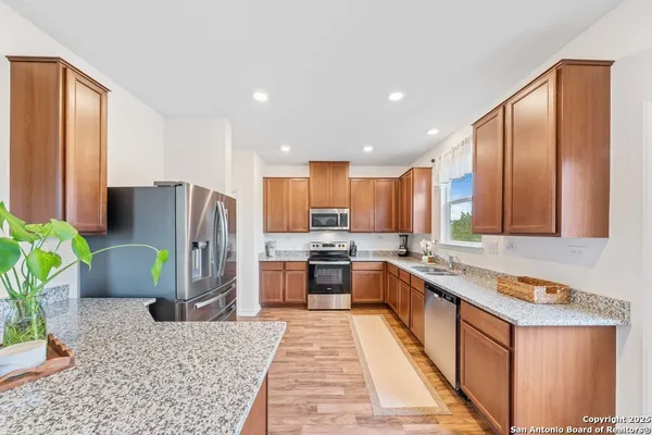 a kitchen with stainless steel appliances granite countertop a refrigerator a stove a sink and a microwave