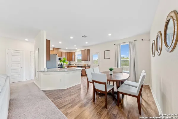 a kitchen with stainless steel appliances kitchen island granite countertop a dining table chairs and a refrigerator