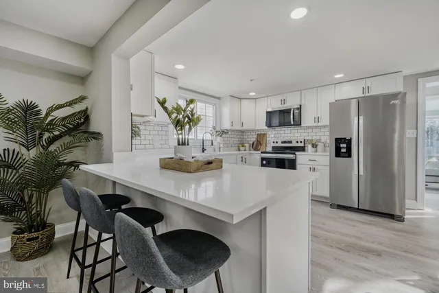 a kitchen with stainless steel appliances a table chairs refrigerator and microwave