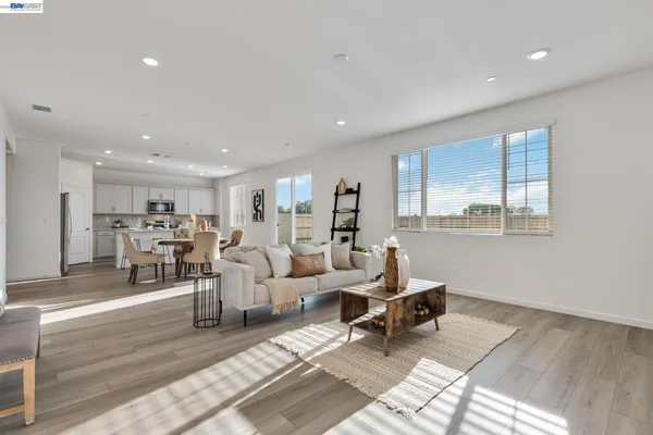 a kitchen with stainless steel appliances kitchen island granite countertop a stove a sink a refrigerator and white cabinets with wooden floor