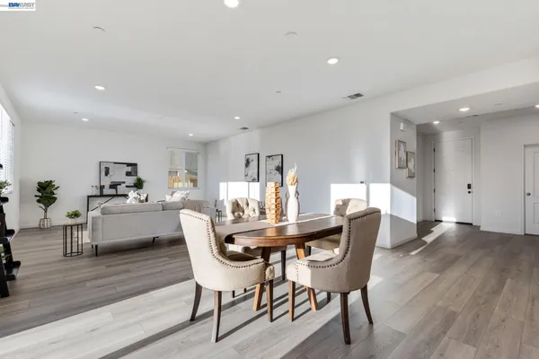 a kitchen with stainless steel appliances kitchen island granite countertop a stove a sink a refrigerator and white cabinets with wooden floor